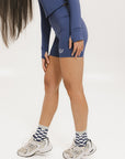 A person wearing indigo and white checkered Charlie Crew Socks with white sneakers and colorful pants.