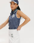 A woman wearing a sleeveless navy blue and white striped Moore Polo golf top with a cap, white skirt, and holding a golf club.