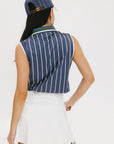 A woman wearing a sleeveless navy blue and white striped Moore Polo golf top with a cap and a white skirt.