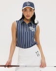 A woman wearing a sleeveless navy blue and white striped Moore Polo golf top with a cap, white skirt, and holding a golf club.