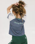 A woman wearing a blue and white striped t-shirt with the words 'chasing balls' on it, paired with green pants.