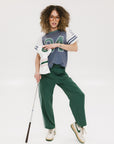 A woman wearing a blue and white striped t-shirt with the number '04' on it, paired with green pants.