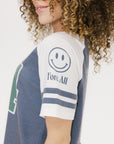 A woman wearing a blue and white striped t-shirt with the number '04' on it, paired with green pants.