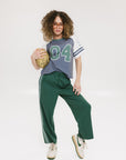 A woman wearing a blue and white striped t-shirt with the number '04' on it, paired with green pants.