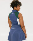 A woman wearing a sleeveless colorblocked mock neck tank top in blue and green with mesh accents and a flat drawstring cord.
