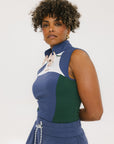 A woman wearing a sleeveless colorblocked mock neck tank top in blue and green with mesh accents and a flat drawstring cord.