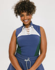 A woman wearing a sleeveless colorblocked mock neck tank top in blue and green with mesh accents and a flat drawstring cord.