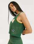 A female model wearing a green sleeveless tank top with 'Fore All' text and a logo on the chest, ribbed armholes, and a round neckline.