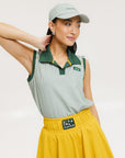 A woman wearing a green striped polo shirt and a matching green cap, with a yellow skirt.
