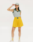 A woman wearing a green striped polo shirt and a matching green cap, with a yellow skirt.