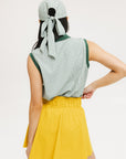 A woman wearing a green striped polo shirt and a matching green cap, with a yellow skirt.