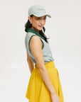 A woman wearing a green striped polo shirt and a matching green cap, with a yellow skirt.