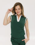A woman wearing a green sleeveless polo with a striped collar and a v-neck.