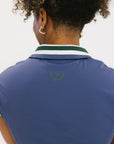 A woman wearing a sleeveless indigo blue polo with a striped collar and v-neck.