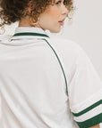A person wearing a white polo shirt with green trim on the collar and sleeves.