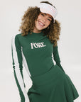 A female model wearing a long sleeve green and white ribbed baselayer top with raglan sleeves and colorblocking.