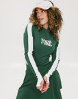 A female model wearing a long sleeve green and white ribbed baselayer top with raglan sleeves and colorblocking.