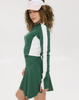 A female model wearing a long sleeve green and white ribbed baselayer top with raglan sleeves and colorblocking.