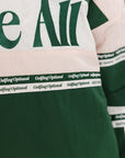 A woman wearing a green and pink racing shirt with colorblocking and text embroidery on it.