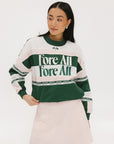 A woman wearing a green and pink racing shirt with colorblocking and text embroidery on it.