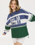 A woman wearing an indigo and green long-sleeved racing shirt with colorblocking and text embroidery.