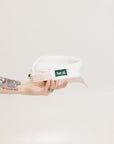 A hand holding a two-toned visor with 'FORE' logo in pink and white colors.