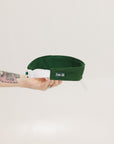 A hand holding a white and green two-toned visor with the word 'FORE ALL' printed on the back.