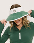A woman wearing a white and green visor with a 'FA' logo on the front.