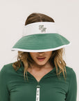 A woman wearing a white and green visor with a 'FA' logo on the front.