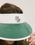 A woman wearing a white and green visor with a 'FA' logo on the front.