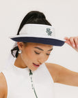 A woman wearing a white and indigo visor with a 'FA' logo on the front and a tied bow on the back.