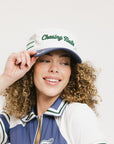 A model wearing a white and blue structured cap with 'Chasing Balls' text and stripes.