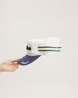 A hand holding a white and blue structured cap with 'Chasing Balls' text and stripes.
