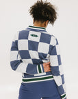 A woman wearing a sleeveless, checkered indigo and white sweater with a mock neck.