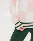 A woman wearing a pink and white checkered intarsia knit sleeveless sweater with a rounded neck.