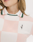 A woman wearing a pink and white checkered intarsia knit sleeveless sweater with a rounded neck.