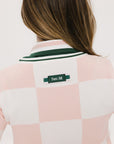 A woman wearing a pink and white checkered intarsia knit sleeveless sweater with a rounded neck.