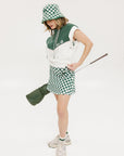 A person wearing a green and white sleeveless hoodie with a hood, matching green and white checkered hat, and green and white checkered skirt. The hoodie has white text and branding on it.