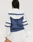 A woman wearing a blue and white hoodie with a half-zip feature and a kangaroo pocket, paired with a white skirt.