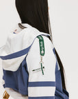 A woman wearing a blue and white hoodie with a half-zip feature and a kangaroo pocket, paired with a white skirt.