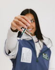 A woman wearing a blue and white hoodie with a half-zip feature and a kangaroo pocket, holding an included tee holder.