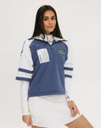A woman wearing a blue and white hoodie with a half-zip feature and a kangaroo pocket, paired with a white skirt.