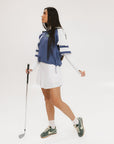 A woman wearing a blue and white hoodie with a half-zip feature and a kangaroo pocket, paired with a white skirt.