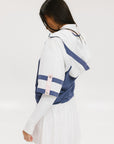 A woman wearing a blue and white hoodie with a half-zip feature and a kangaroo pocket, paired with a white skirt.