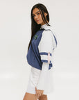 A woman wearing a blue and white hoodie with a half-zip feature and a kangaroo pocket, paired with a white skirt.