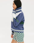A person wearing a blue and white striped half zip top with long sleeves and a high collar, paired with checkered green and white shorts.