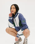 A woman wearing a half zip sports top with colorblocking in blue, white, and green, and ribbed detailing around the collar, cuffs, and hem.