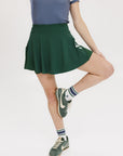 A person wearing a green skirt with a mesh back, paired with a blue top and green sneakers. The skirt has a high waist and a mid-thigh length cut.