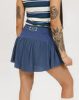 A person wearing a blue skirt with a mesh back, along with a striped top and white socks with green stripes. The image focuses on the skirt which has a sports-inspired design.