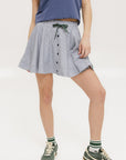 A seersucker skirt with subtle stripes, featuring a flat drawstring, faux buttons down the front, and side seam pockets.